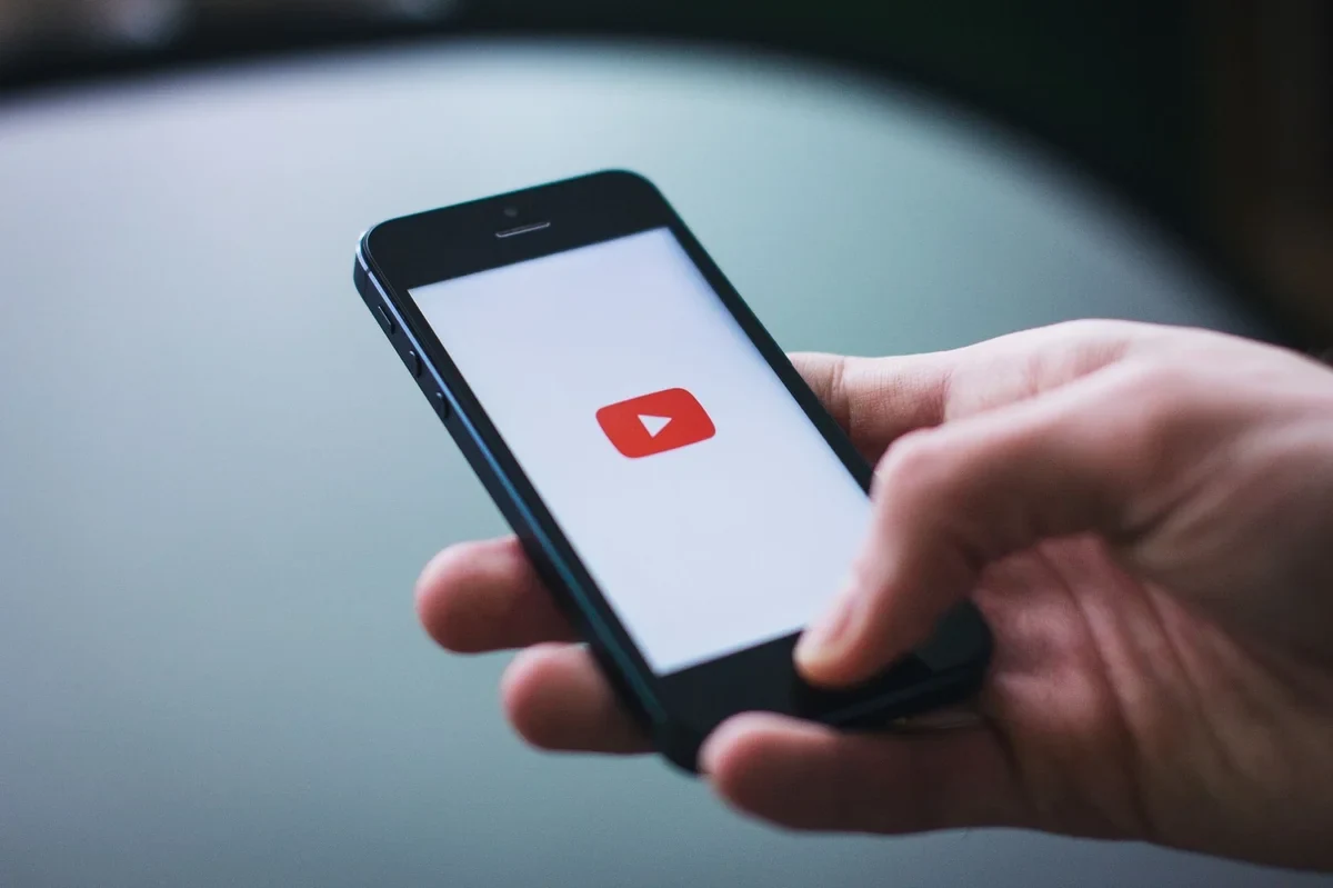 Bàn tay cầm điện thoại xem YouTube, minh họa quy trình tăng like không cần mật khẩu