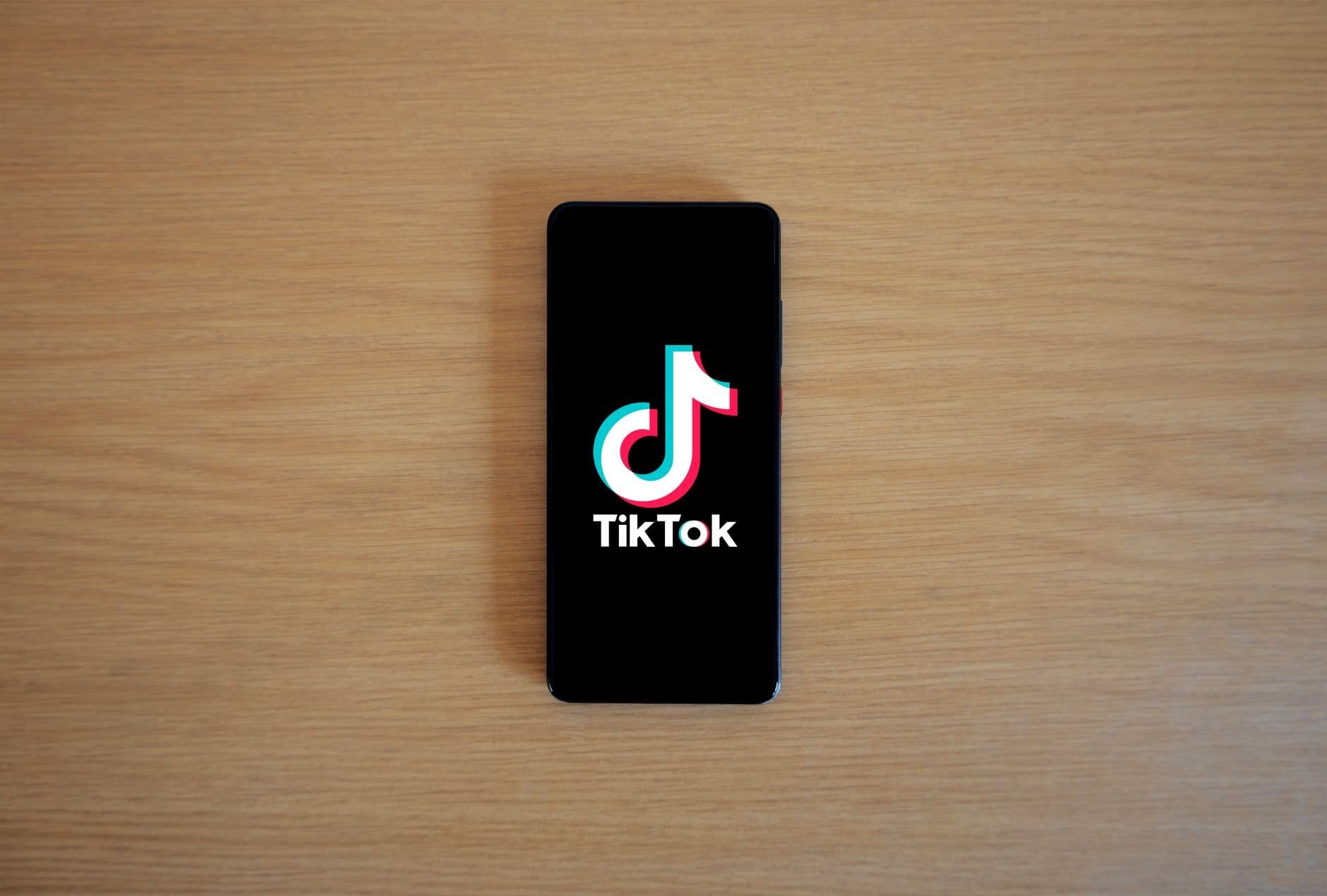 Điện thoại hiển thị logo TikTok trên mặt bàn gỗ