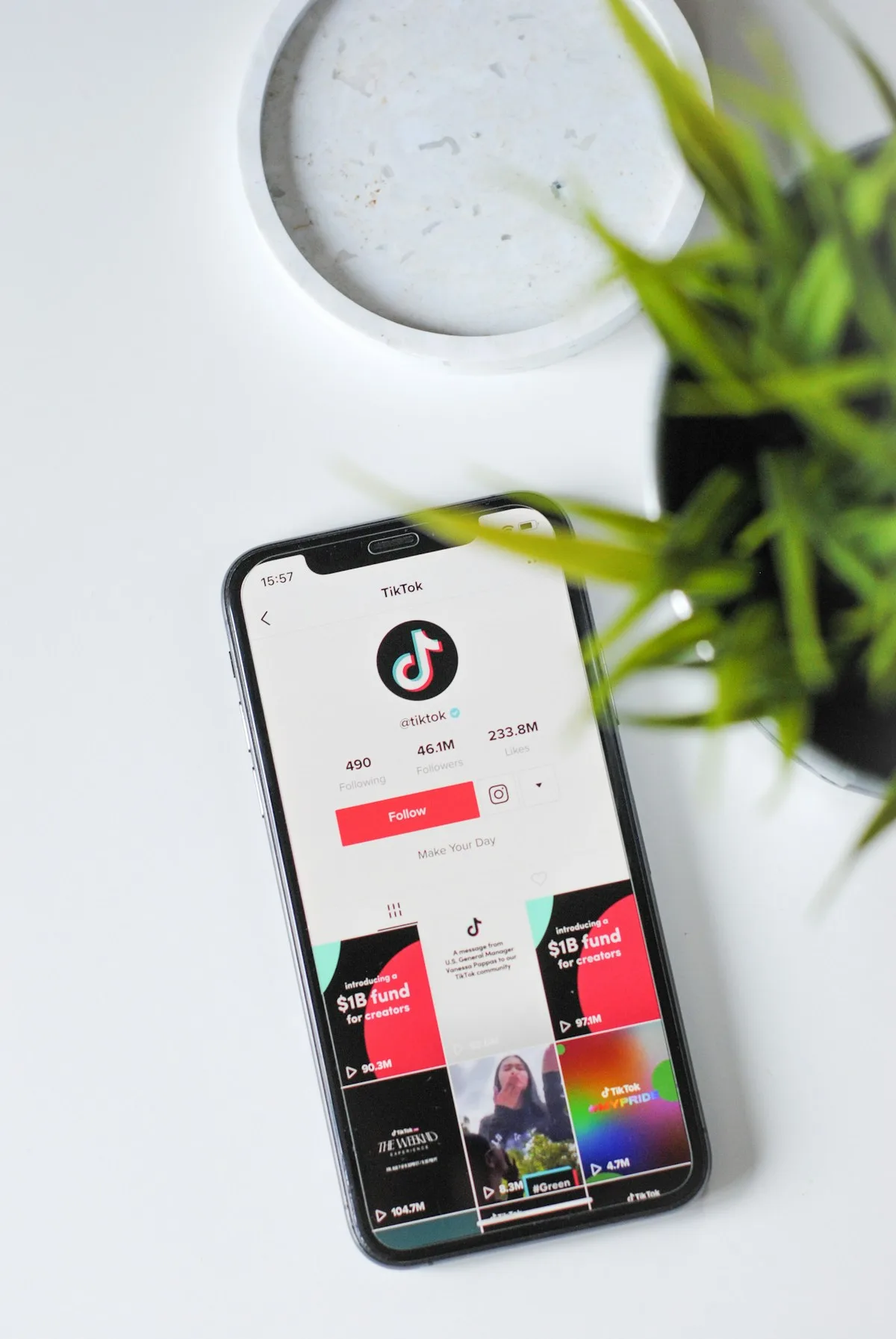 Điện thoại mở TikTok cạnh chậu cây trên bàn trắng